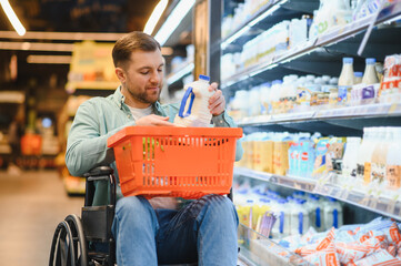 Customer using wheelchair choosing milk in supermarket dairy section