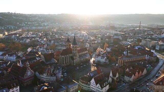 Esslingen am Neckar medieval city dominates composition, distinctive red-tiled roofed buildings and multiple church spires prominent, Neckar River visible flowing through valley, drone glide, Germany