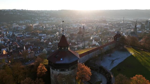 Esslingen's medieval castle tower rises above the meandering Neckar river in this golden hour aerial perspective, Stuttgart region Baden-W&uuml;rttemberg, medieval city architecture visible, Germany