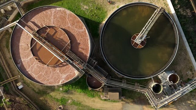 Top down aerial view of industrial pipework and clarifying tanks filled with brown water from sugar production industrial operations. Newark, United Kingdom.
