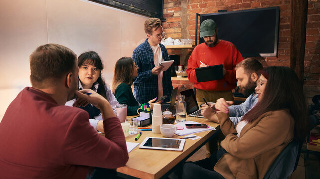 Team discussion around table in modern startup office. Concept of creative collaboration, open communication, professional teamwork for corporate branding and content. - Powered by Adobe