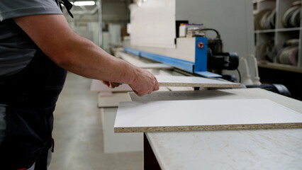 Furniture factory worker operating edge banding machine