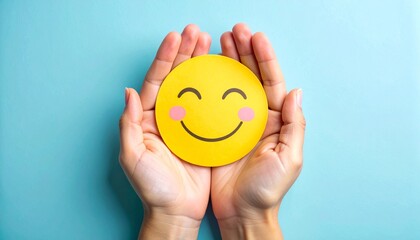 Hands cupping yellow smiley face with closed eyes and pink cheeks on light blue background