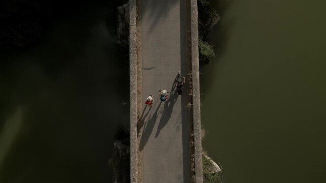 Two tourists crossing a medieval bridge in northern Spain. Camino Frances route. Drone shot.