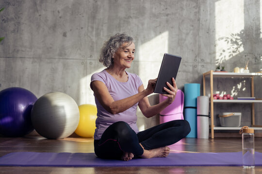 Senior woman exercising at home using digital tablet
