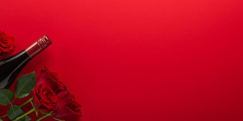 Red rose flowers and wine bottle on red background top view. Valentine's day, 14 February, birthday, 8 march women's day gift. Love and romance.