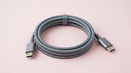 A high-speed USB-C phone charger cable coiled neatly on a light pink background