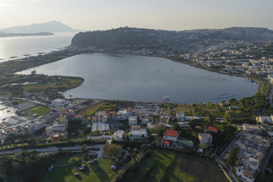 Aerial view of the serene Miseno Lake mirroring the sky, nestled between the verdant hills and the coastal town, a blend of nature and civilization., Bacoli, Campania, Italy.