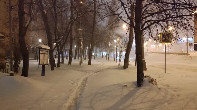 Heavy winter snowfall in big city in early morning. City roads and sidewalks covered with snow. Path trampled in snowdrift. Lone pedestrians go to work. Utilities haven't started cleaning yet