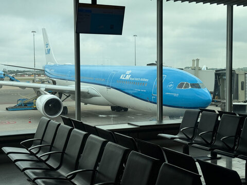 amsterdam, netherlands - may 30 2025: A Klm plane is visible outside the terminal windows at Schiphol Airport. Empty seats line the waiting area.