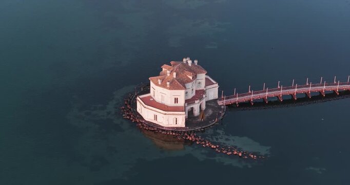 Aerial view of the isolated Casina Vanvitelliana connected to the mainland by a bridge, standing out against the water, Fusaro Lake, Bacoli, Italy.