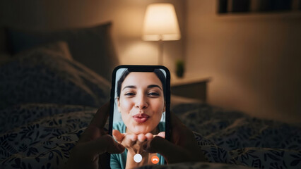 Person holds phone with woman on video call blowing kiss, staying connected through virtual communication using modern technology for Valentines day