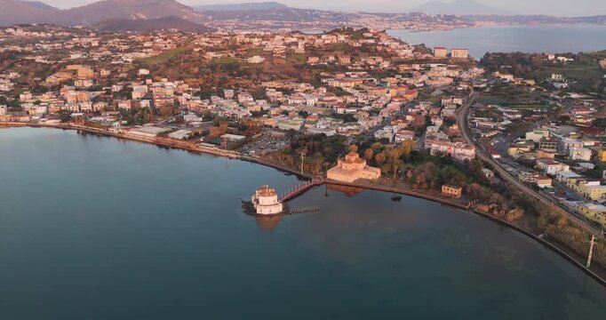 Aerial view of Casina Vanvitelliana, a captivating island structure connected by a wooden bridge, amidst the tranquil waters, Fusaro Lake, Bacoli, Italy.