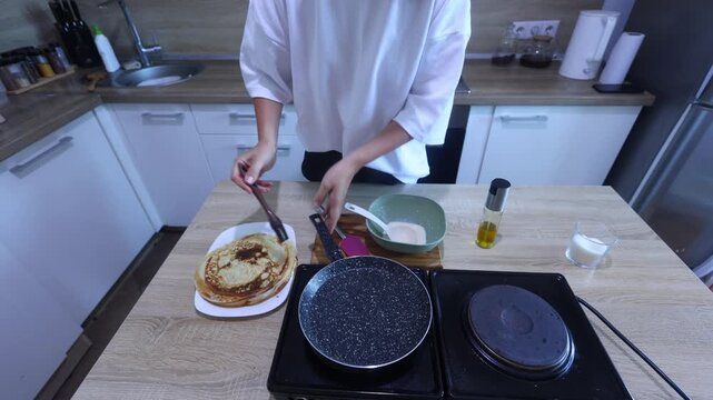 A cook pours batter into a hot pan and swirls it for a flawless, even layer. Ideal for beginners learning the art of making delicate, golden crepes at home.