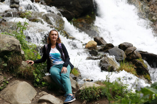 Woman tourist enjoying mountain waterfall in Teberda Nature Reserve