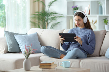 Obraz premium Woman in blue wearing headphone using tablet at home
