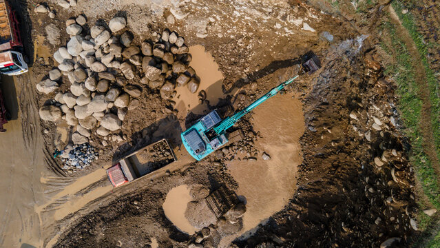 Excavator and dump truck working in rock and sand quarry, Construction and mining site view from above.