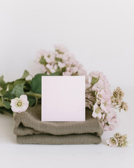 Elegant wedding card mockup set on a cozy folded knit with soft flowers adding a touch of romance and charm to the display in a serene indoor setting
