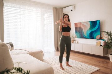 indoor fitness class with lively energy, young woman performing home exercise routine on tablet