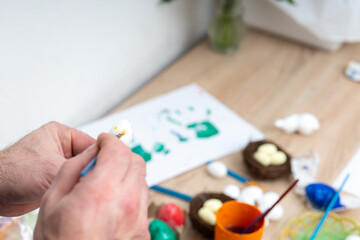 Preparing for Easter painting bright eggs on wooden table in cozy home
