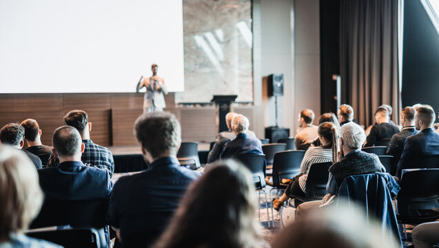 Speaker giving a talk in conference hall at business event. Rear view of unrecognizable people in audience at the conference hall. Business and entrepreneurship concept