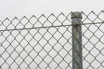 Galvanized chain link fence security barrier against grey sky