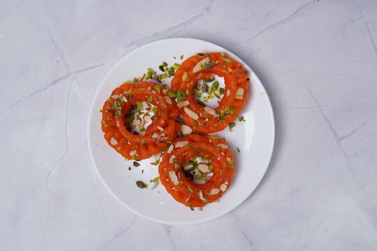 Imarti is a classic Indian sweet made from urad dal batter, deep-fried into intricate flower-shaped spirals and soaked in aromatic sugar syrup. Known for its crisp exterior and juicy interior, this tr