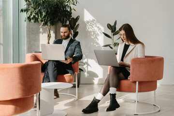 Business colleagues working on laptops in modern office lounge