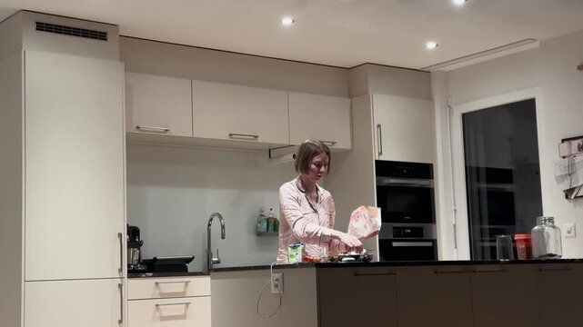 A woman prepares a late-night snack in a modern kitchen. Concept of midnight hunger, home comfort, everyday lifestyle, and casual cooking at night.