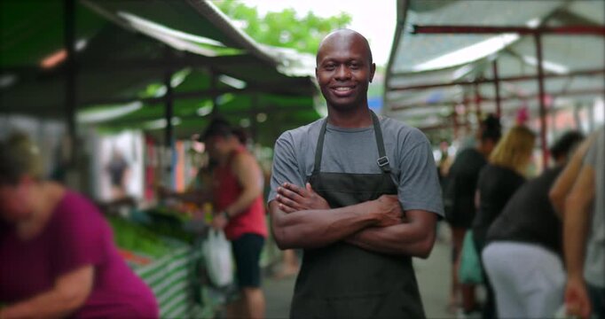 African American street vendor with arms crossed at outdoor market conveying confidence stability and pride in everyday local food commerce