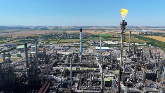Aerial view of Humber Refinery, a vast industrial complex with pipes, tanks, and a flare stack emitting bright flames, Immingham, United Kingdom.