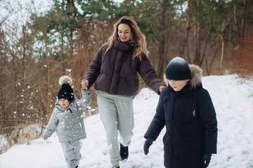 Mother and children playing, walking outdoors in winter forest © dsheremeta