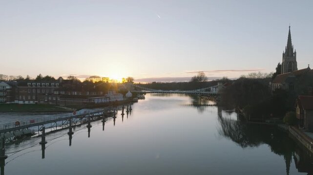 Marlow, UK Sunset mid shot flying over river towards bridge at sunset.