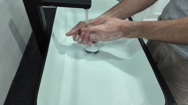 Hands are thoroughly washed with soap under a steady stream of water in a sleek sink, demonstrating effective hygiene practices and the importance of cleanliness