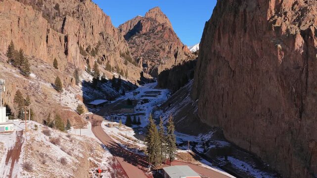 A cinematic aerial view captures the dramatic contrast between deep canyon shadows and a sunlit mountain peak. Steep rocky walls and rugged textures define the immense scale of this Southwest terrain.