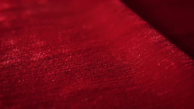 Abstract red fabric texture close up with shadow play and soft lighting