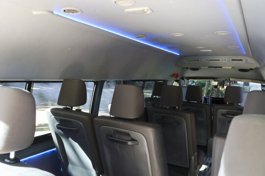 Interior of modern passenger van with comfortable grey leather seat and blue luxury light on ceiling for travel transport and vip shuttle service