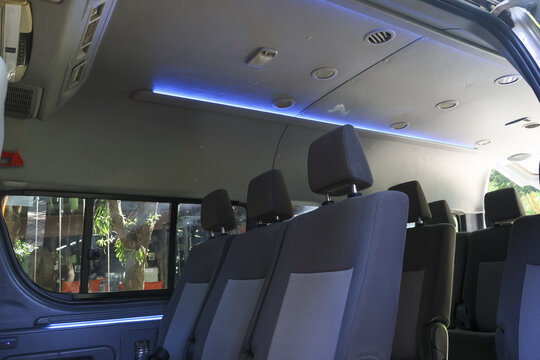 Modern gray minibus passenger seats interior detail with empty seat row and blue ceiling light offering comfortable and relaxing journey for commuter travel transportation