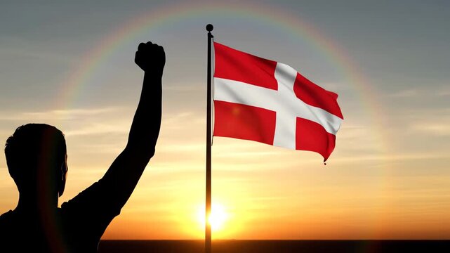 Man Celebrating with Raised Fist near Danish Flag at Sunset