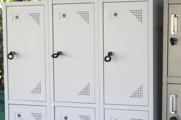Clean orderly white metal locker cabinets row with secure black handles in quiet room offering safe...