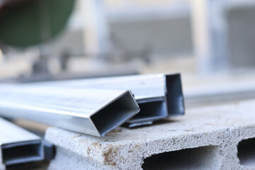 Construction site featuring rectangular metal steel tube beams stacked grey cement block with...