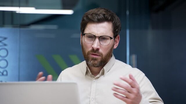 Frustrated businessman sitting in office having trouble working on laptop. Worried male employee looking at screen, experiencing technical problem, mistake, or computer error at workplace. Close up