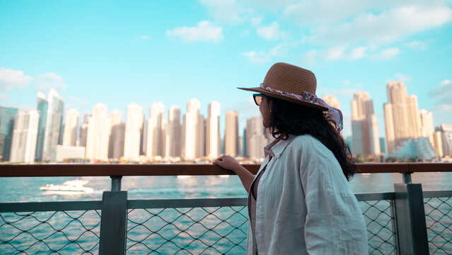 woman standing by waterfront overlooking city skyline from Bluewater island Dubai, Dubai Ain, JBR beach walk, Dubai Marina
