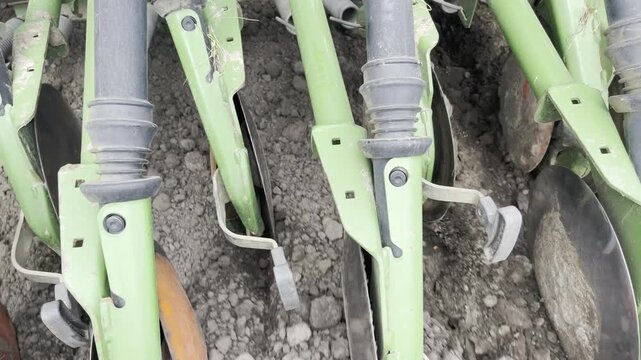 Dynamic close-up of an agricultural seeder in action, showing seeds dropping into soil holes. Modern farming process highlighting precision planting and crop production.
