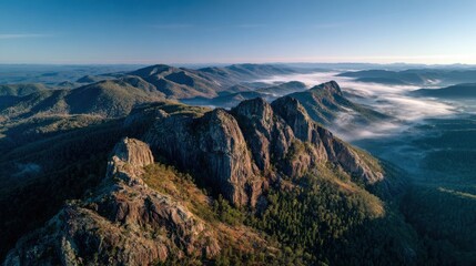 Jagged peaks rise above a misty valley, illuminated by soft morning light