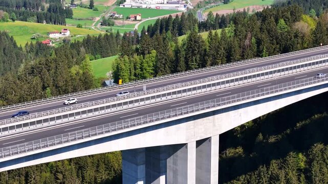Aerial view of the Lavanttal bridge shows cars traversing the concrete structure amidst a vibrant landscape, Wolfsberg, Carinthia, Austria.