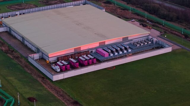 Close up aerial drone view of industrial data center exterior featuring high tech cooling fans ventilation systems and backup power generator units