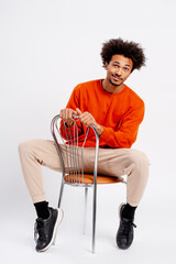 Young man with afro hairstyle sitting on chair looking at camera in studio