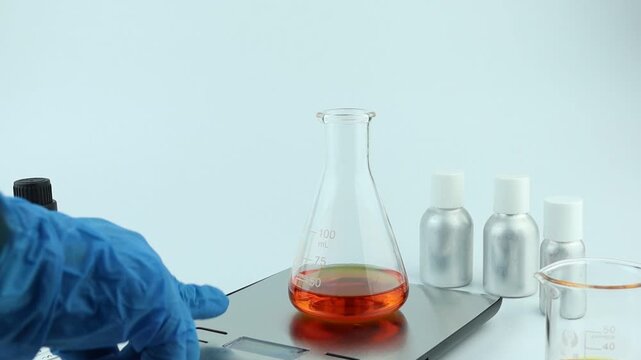 chemical beaker or flask is used on white table with blotting paper fragrance bottle and essential oil bottle are used to blend nice scent for making perfume and reed diffuser by perfumer in lab test