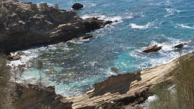 Slow motion landscape showing inlet ocean cove reef surrounded by rocky headland terrain and bushland forest trees along the Malua Bay coastline South Coast NSW Australia travel tourism and nature